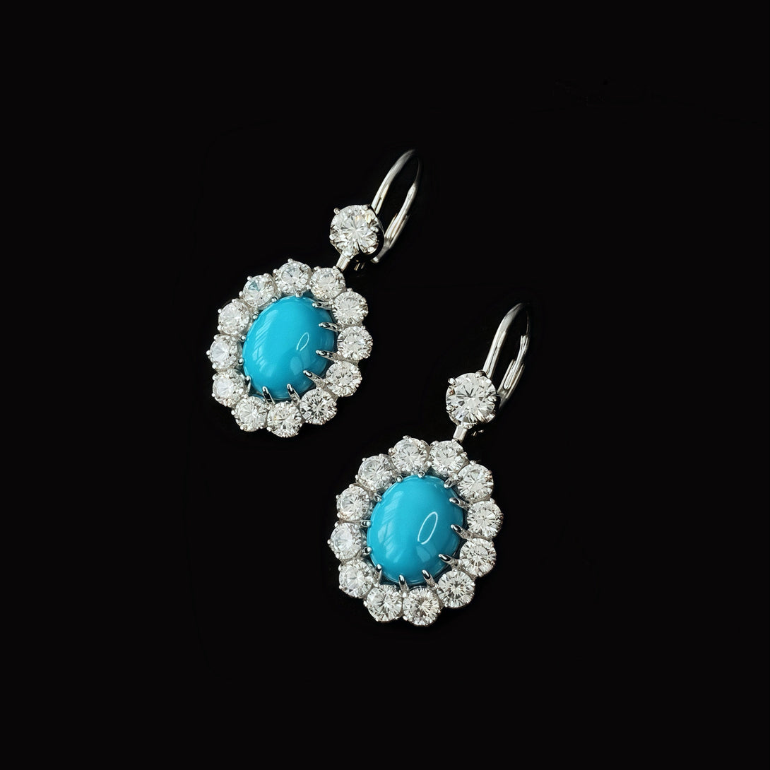 Pair of earrings with turquoise stones and diamond accents on a black background