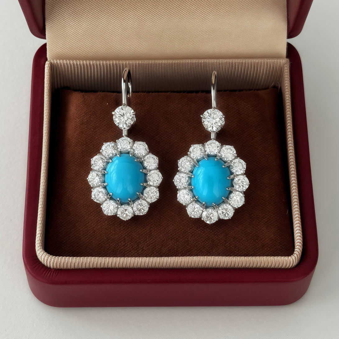 Turquoise and diamond earrings in a red jewelry box on a white background